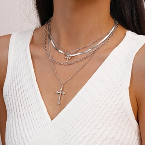 Close-up of a layered silver necklace with sparkling cross pendants on a female neck