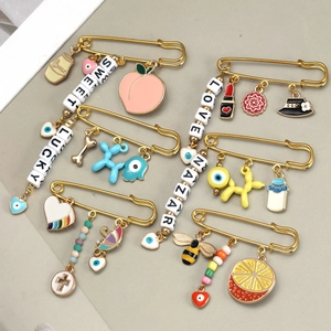 Close-up of golden pins with colorful charms like evil eye, balloon dog and enamel beads