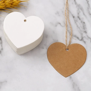 Flat lay of heart-shaped wood and kraft paper tags with twine on marble background