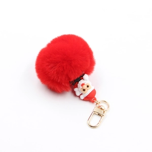 Detail of red pompom keychain with Santa Claus figurine and golden metal clasp for bags