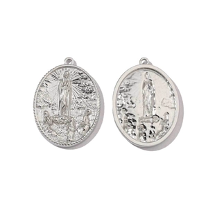 Macro detail of oval stainless steel Virgin Mary religious medals with embossed scene