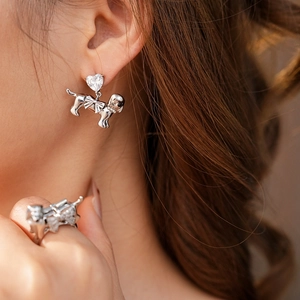 Detail shot of a model wearing a puppy-shaped earring with a heart-shaped diamond accent