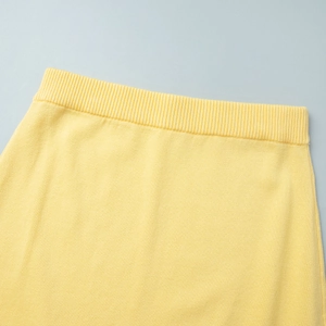 Detailed close-up of ribbed elastic waistband on yellow knitted skirt set for women