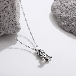 Detailed close-up of a vintage silver cowboy boot pendant with sparkling zircon on a wavy chain