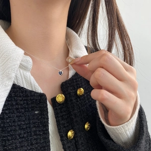 Close-up of S925 silver necklace with blue heart zircon pendant on a model wearing tweed