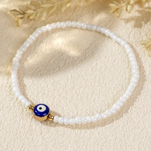 Minimalist evil eye beaded bracelet with blue eye charm and white seed beads on stone