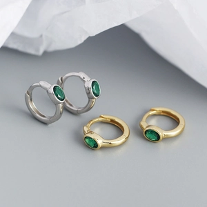 Detail of minimalist silver and gold oval green zircon hoop earrings in studio lighting