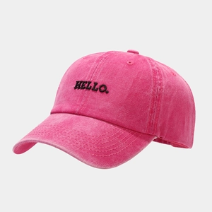 Detailed view of washed pink baseball cap featuring black HELLO embroidery and vintage texture