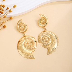 Detailed view of gold spiral seashell earrings with textured vintage metal finish