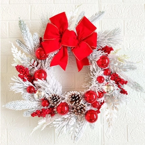 Detail of Christmas wreath with frosted pine branches, red berries, and pine cones