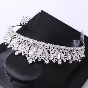 Close-up of a silver bridal crown with rhinestones and combs on a black stand
