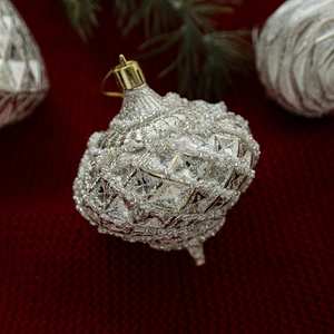 Pallina di Natale argento antico con perline bianche su sfondo rosso lavorato a maglia
