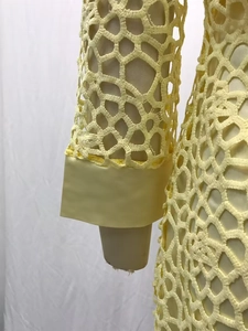 Gros plan sur la broderie en dentelle jaune de la robe à manches longues et doublure