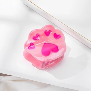 Detailed view of pink cat paw hair claw clip with heart accents on a white surface