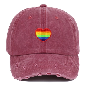 Close-up of rainbow heart embroidery and distressed brim on washed red baseball cap
