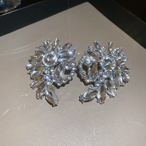 Detailed view of silver flower earrings with sparkling rhinestones on a leather surface