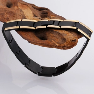 Macro detail of men's matte black and mirror gold modular link bracelet on grey background