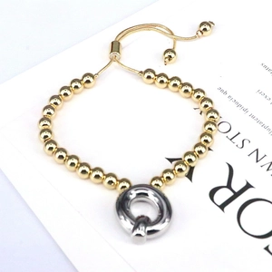 Detail of gold beaded bracelet with silver twisted ring charm and adjustable slider chain