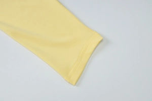 Gros plan du poignet d'une robe jaune clair avec texture tricotée et doubles coutures