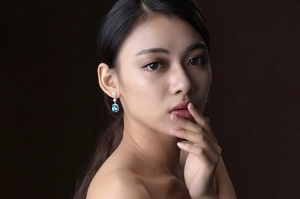 Macro shot of long silver earrings with square blue gemstones on female model