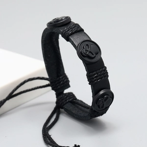 Détail d'un bracelet en cuir tressé noir avec trois crânes et cordon de serrage réglable