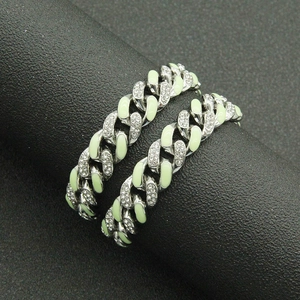 Macro detail of iced-out Cuban link chains with green enamel and sparkling rhinestones