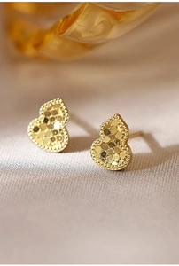 Macro view of gold gourd earrings with textured surface and intricate beaded metal edges