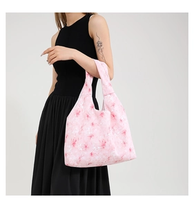Detailed view of pink floral canvas tote bag held by a model in a black dress
