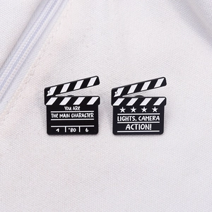 Creative movie clapperboard enamel pins on canvas background for fashion decoration