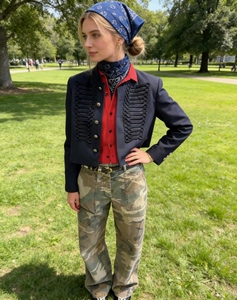 Detail of navy military jacket with tassels, red shirt and camo cargo pants on model