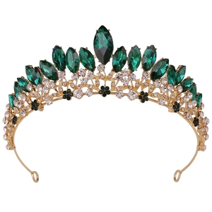 Close-up of golden bridal crown with emerald green gems and sparkling clear crystals