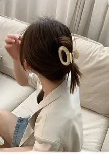 Close-up of cream acetate geometric round hair claw clip worn on high ponytail hairstyle