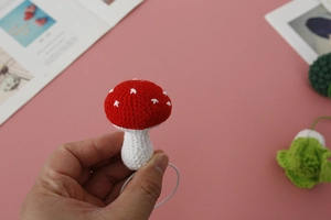 Close-up of handmade crochet mushroom hair tie with red cap and white polka dots