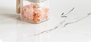 Close-up of a clear spice jar with pink Himalayan salt and a white spoon on marble