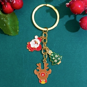 Golden Christmas keychain with Santa, reindeer and rhinestone tree on a festive background