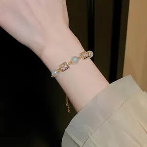 Elegant gold adjustable bracelet with square zircons and mermaid pearls on wrist