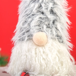 Close-up of plush Christmas gnome with long white fur beard and knitted hat on red