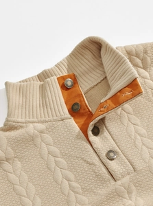 Detail of cable knit texture and contrasting orange canvas placket on a men's sweater