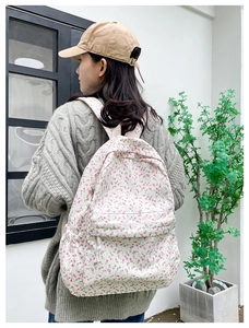 Close-up of floral canvas backpack featuring pink flower prints and front zipper pocket