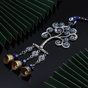 Blue evil eye keychain with silver life tree, tassels, and brass bells on dark background