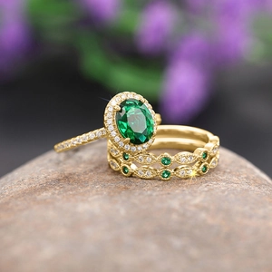 Macro shot of oval green gemstone ring set with sparkling diamonds on grey stone