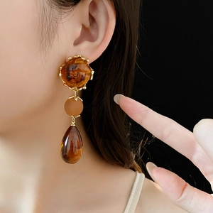Macro shot of vintage drop earrings with amber beads and dark brown teardrop pendants