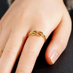 Detailopname van een minimalistische gouden oneindigheidsring aan de vinger met leren achtergrond