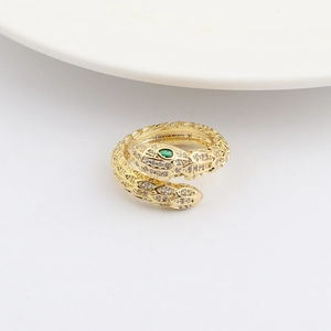Dettaglio macro di anello a serpente dorato con zirconi brillanti e occhi verdi