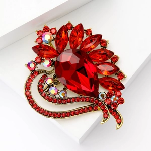 Macro detail of retro red teardrop crystal brooch with bronze hollow base and colorful accents