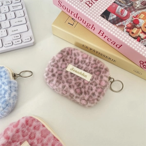 Dettaglio di custodie per AirPods in peluche leopardato con ganci in metallo e logo