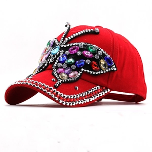 Detail of red baseball cap featuring a large colorful rhinestone butterfly ornament