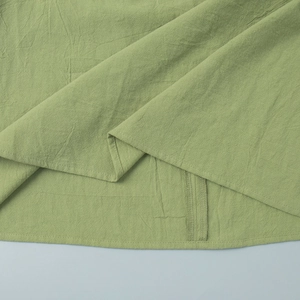 Detail of light green cotton dress hem featuring neat stitching and linen-like texture