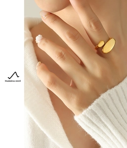 Close-up of golden irregular open ring in stainless steel worn on finger with soft knitwear
