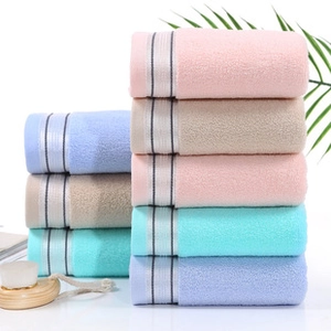 Close-up of stacked soft coral fleece fruit towels in pink, blue, beige, and cyan colors